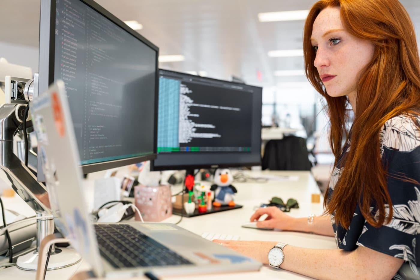 Desarrolladora trabajando con código en dos monitores
